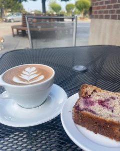 loganberry coffee cafe and a latte on a metal table outside Thatcher's Coffee in Vancouver