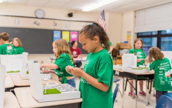 Kids in green camp shirts working in a science lab