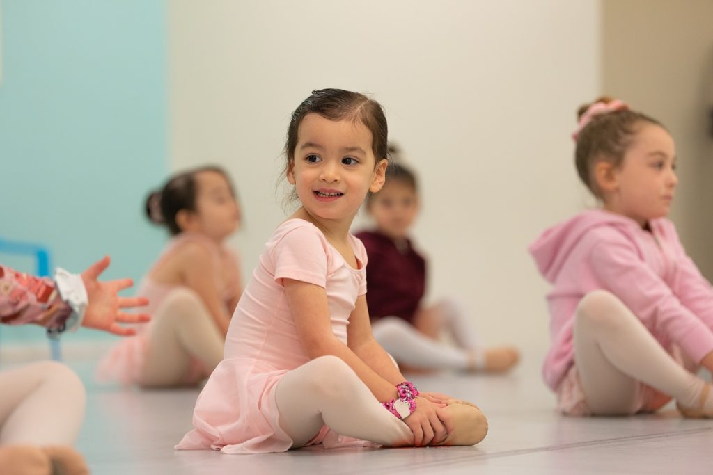 young ballerina in pink tutus sitting on the floor