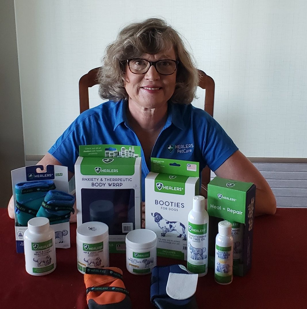 Terri sitting at a table with Healer's Pet Care products in front of her