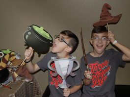 two kids playing with Harry Potter props including a cauldron and a hat in downtown Camas