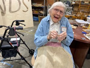 Betty Eves sitting and sanding items at Friends of the Carpenter