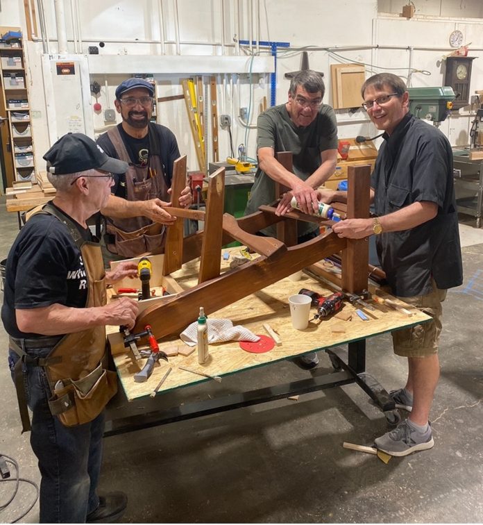 men working on building a wooden chair at Friends of the Carpenter