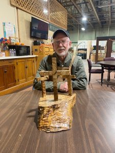 Cal Swanson sitting at a table with a woodworking item at Friends of the Carpenter